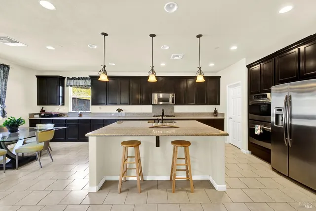 a kitchen with stainless steel appliances granite countertop stainless steel appliances a sink a stove top oven a counter space and cabinets