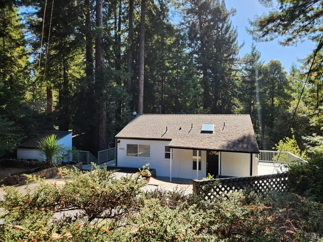 a view of a wooden house with a yard and large trees