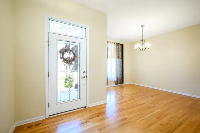 an empty room with wooden floor mirror and windows