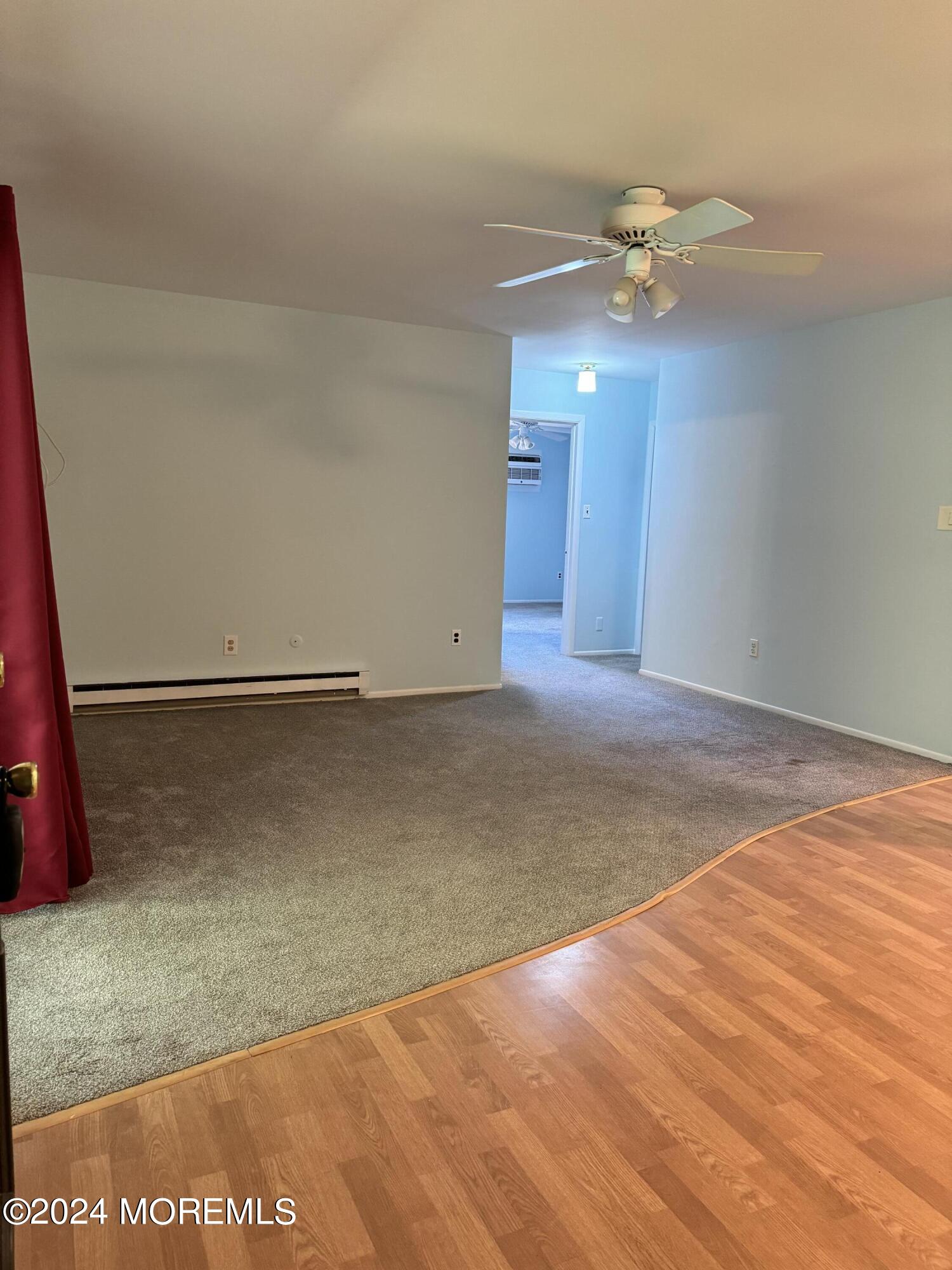 an empty room with wooden floor and fan