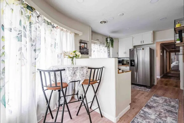 a kitchen with stainless steel appliances granite countertop a dining table chairs and a refrigerator