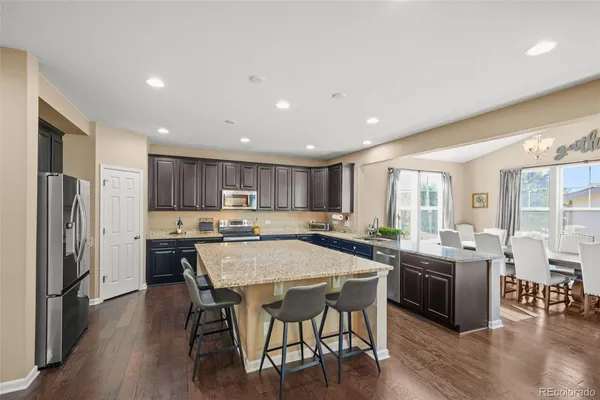 a kitchen with stainless steel appliances a dining table chairs stove refrigerator and cabinets