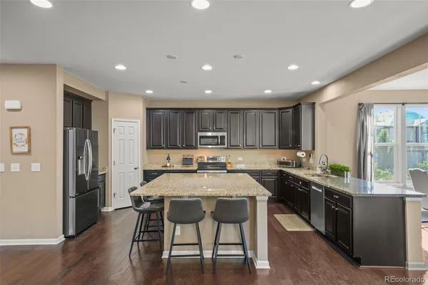 a kitchen with stainless steel appliances granite countertop a table chairs sink refrigerator and cabinets