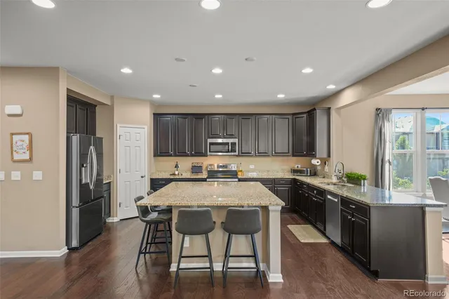 a kitchen with stainless steel appliances granite countertop a table chairs sink refrigerator and cabinets