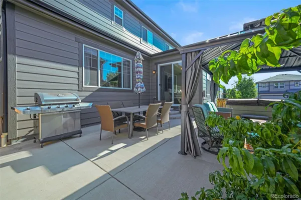 a view of a patio with table and chairs potted plants and floor to ceiling window