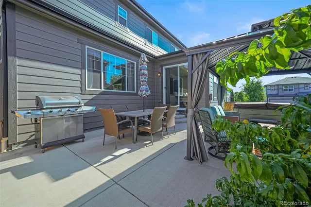 a view of a patio with table and chairs potted plants and floor to ceiling window