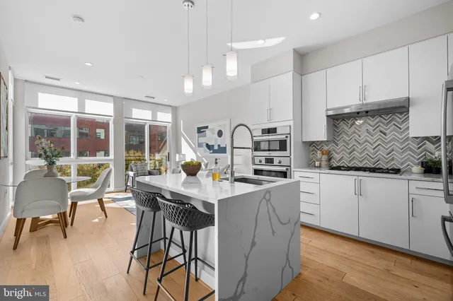 a kitchen with stainless steel appliances kitchen island granite countertop a stove a sink a dining table and chairs with wooden floor