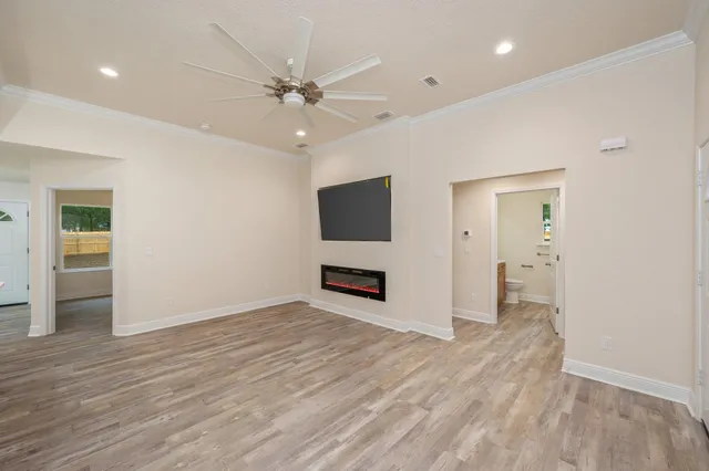 an empty room with wooden floor and ceiling fan
