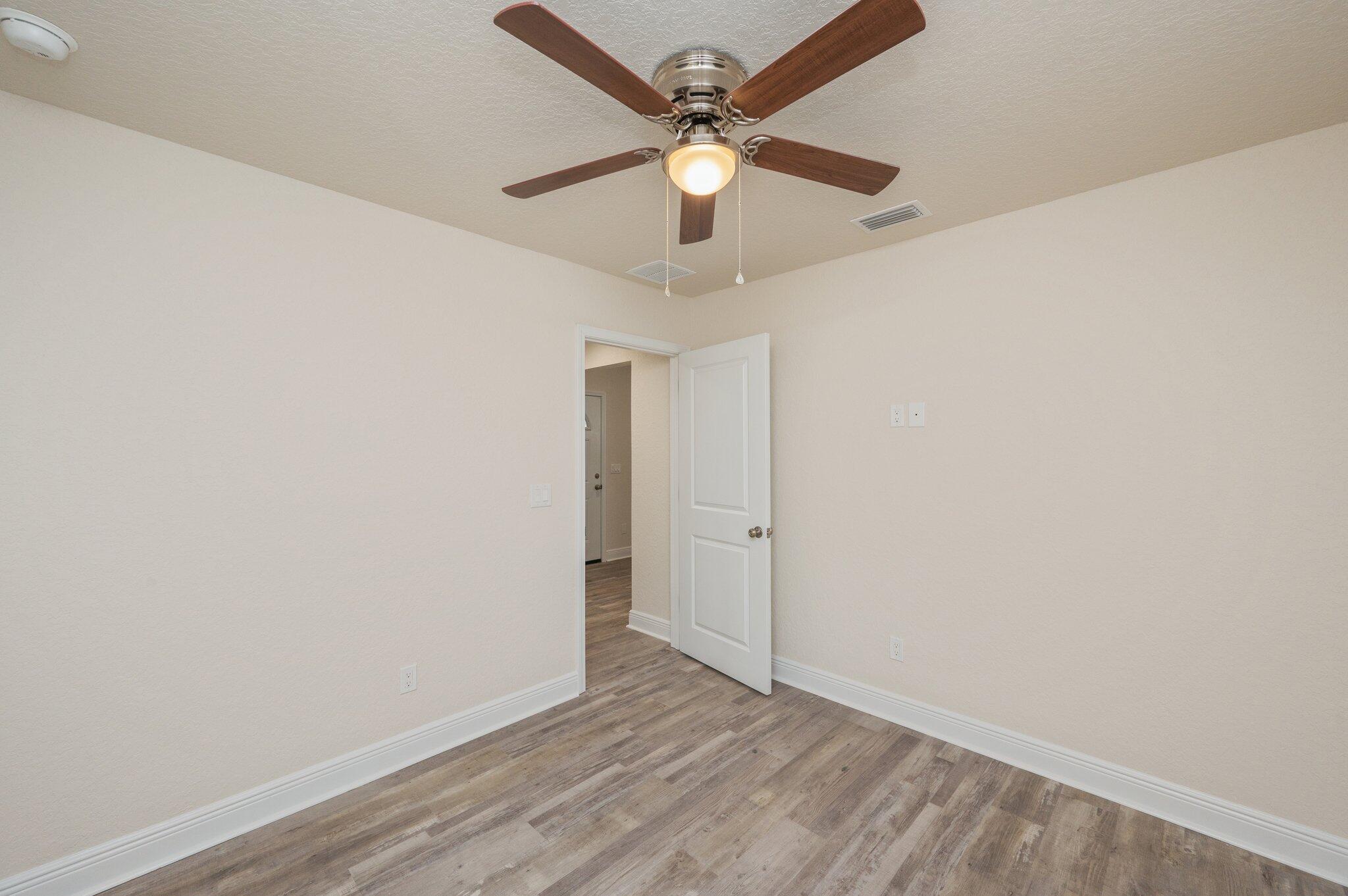 609 East Chestnut Avenue Crestview, FL 32539 - Photo 22 of 31 a view of an empty room with window a ceiling fan and wooden floor