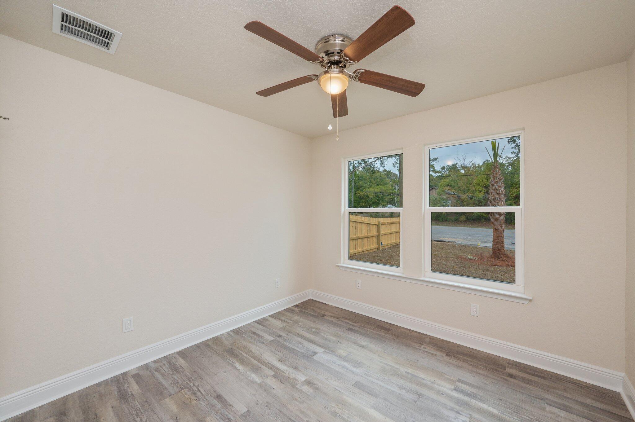 609 East Chestnut Avenue Crestview, FL 32539 - Photo 25 of 31 an empty room with wooden floor ceiling fan and windows