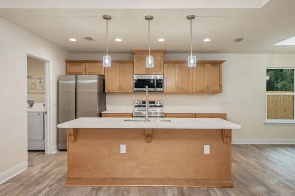 a view of a kitchen with kitchen island a counter top space stainless steel appliances and a ceiling fan