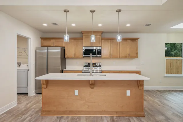 a view of a kitchen with kitchen island a counter top space stainless steel appliances and a ceiling fan
