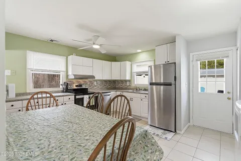 a kitchen with stainless steel appliances granite countertop a refrigerator a sink a stove a dining table and chairs