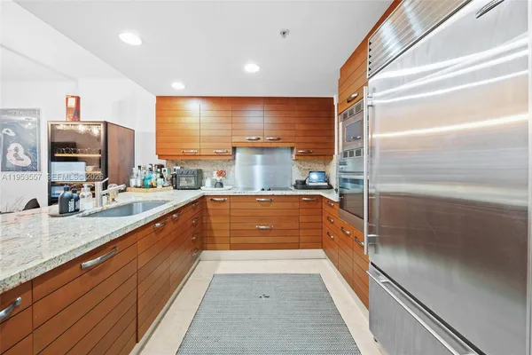 a large kitchen with kitchen island a counter top space a sink and stainless steel appliances