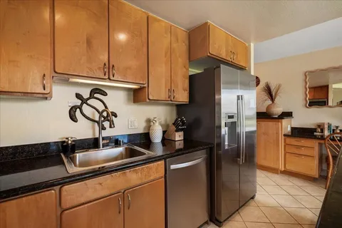 a kitchen with stainless steel appliances granite countertop a sink a refrigerator and a stove top oven