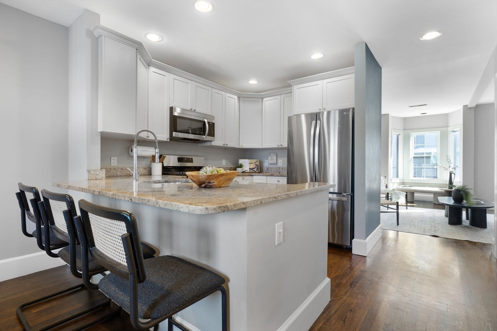 20 Sullivan Street, Unit 2 Boston, MA 02129 - Photo 9 of 25 a kitchen with stainless steel appliances granite countertop a stove a refrigerator a sink a dining table and chairs with wooden floor