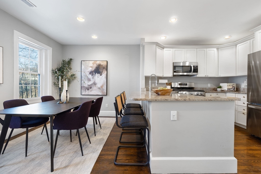 20 Sullivan Street, Unit 2 Boston, MA 02129 - Photo 10 of 25 a kitchen with kitchen island granite countertop a stove a sink a microwave a dining table and chairs