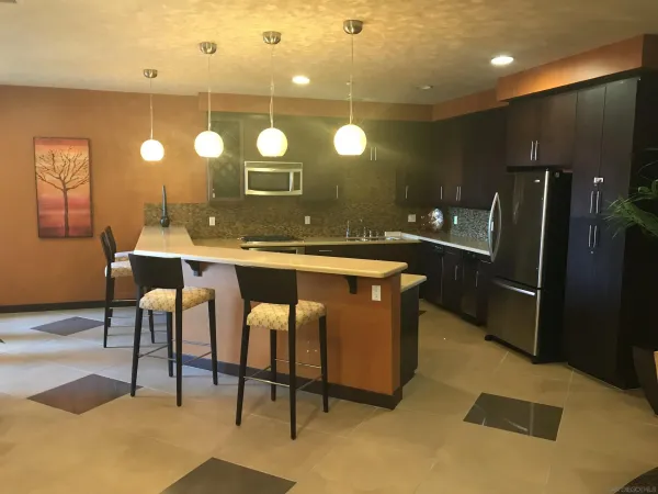 a kitchen with stainless steel appliances kitchen island a table chairs sink and wooden floor
