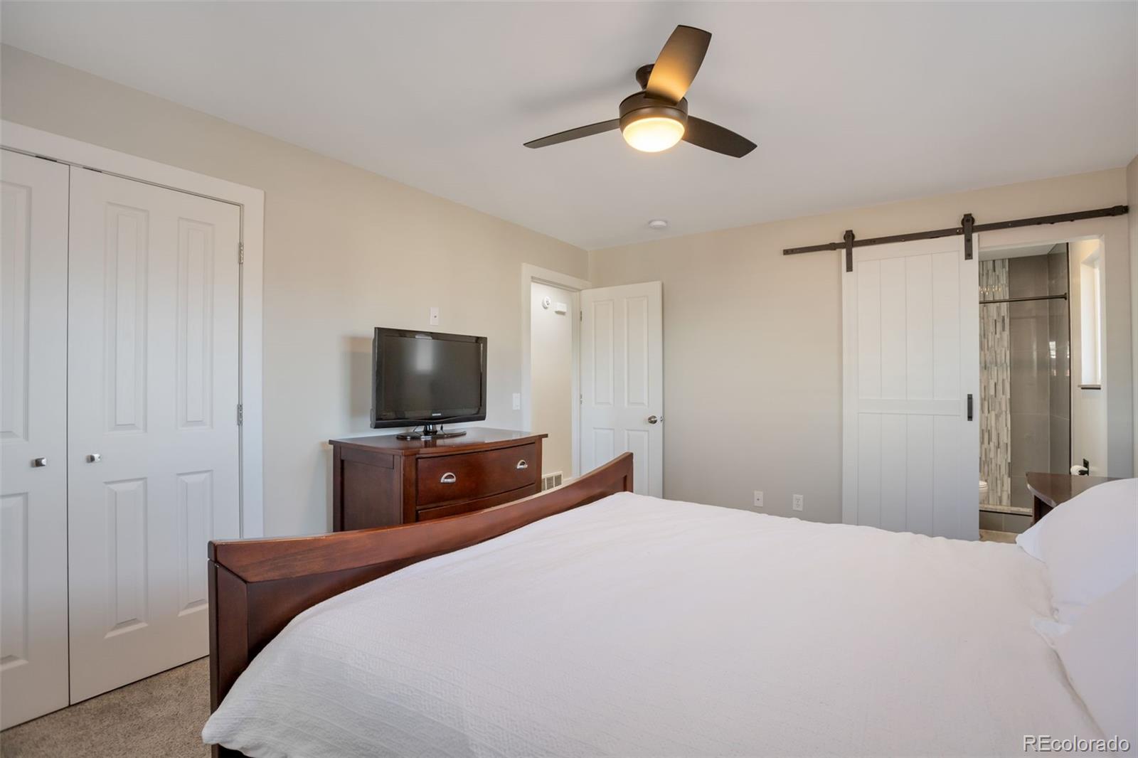 6221 South Logan Court Centennial, CO 80121 - Photo 19 of 30 a bedroom with a bed and a flat screen tv