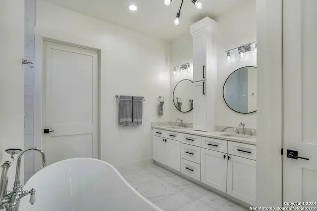 a spacious bathroom with a granite countertop double vanity sink and a mirror