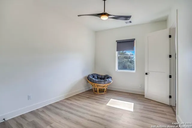 a view of an empty room with a window and wooden floor