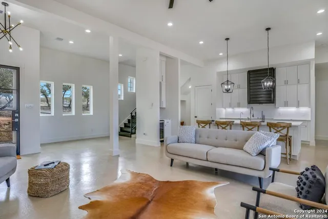 a living room with furniture kitchen view and a chandelier