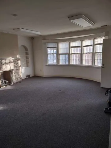 a view of an empty room with a fireplace and a window