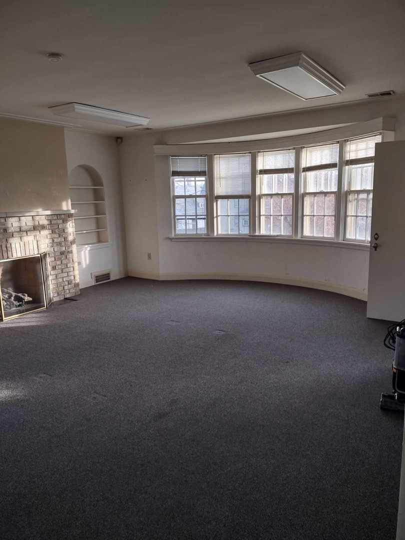 a view of an empty room with a fireplace and a window