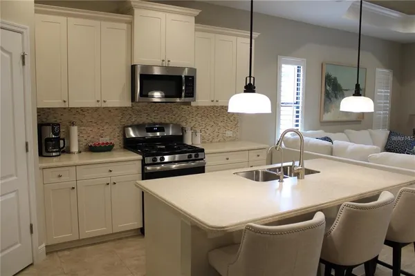 a kitchen with a sink a microwave a stove and cabinets