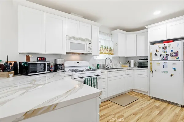 a kitchen with kitchen island granite countertop white cabinets sink and white appliances