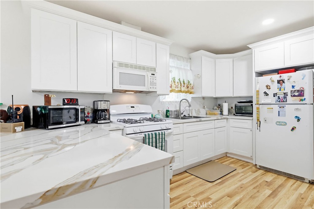 924 West 134th Place Compton, CA 90222 - Photo 19 of 45 a kitchen with kitchen island granite countertop white cabinets sink and white appliances