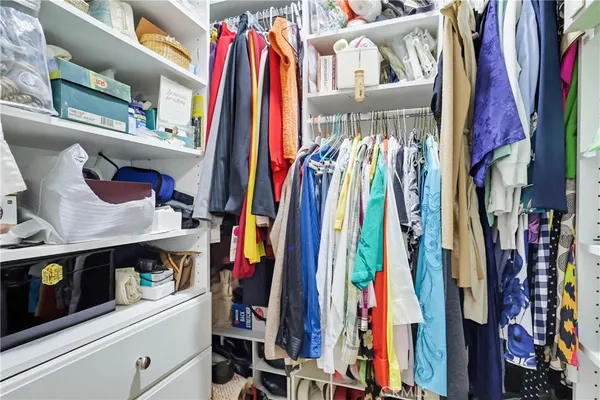 a view of walk in closet with clothes and shoes