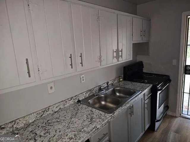 a kitchen with granite countertop white cabinets and a stove