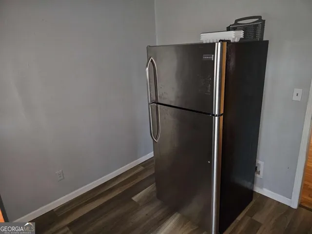 a view of a refrigerator in kitchen and an empty room