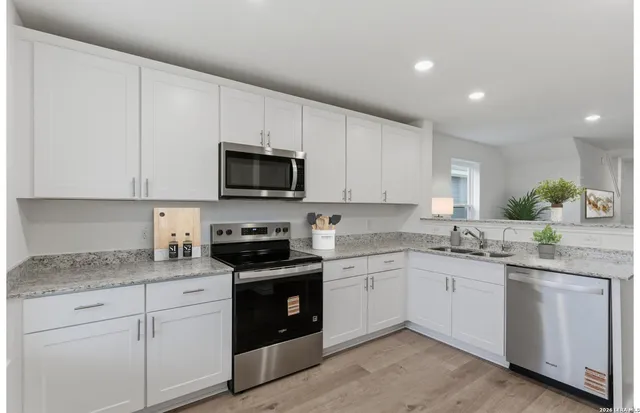 a kitchen with white cabinets stainless steel appliances and sink
