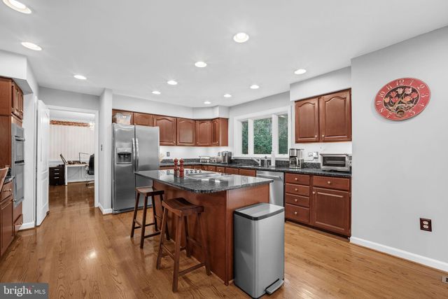 a kitchen with stainless steel appliances granite countertop a stove top oven a refrigerator a sink and dishwasher a oven with wooden floor