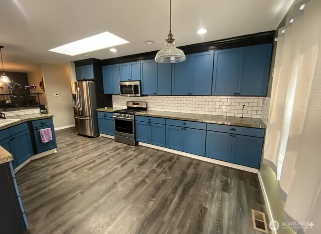 a kitchen with stainless steel appliances granite countertop wooden cabinets a sink dishwasher a stove and a refrigerator