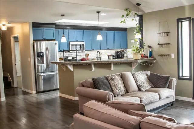 a living room with stainless steel appliances furniture and kitchen view