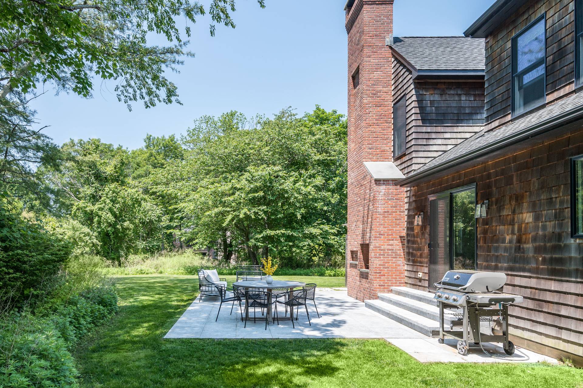 87 Accabonac Road East Hampton, NY 11937 - Photo 17 of 20 a view of a patio with table and chairs potted plants and a large tree