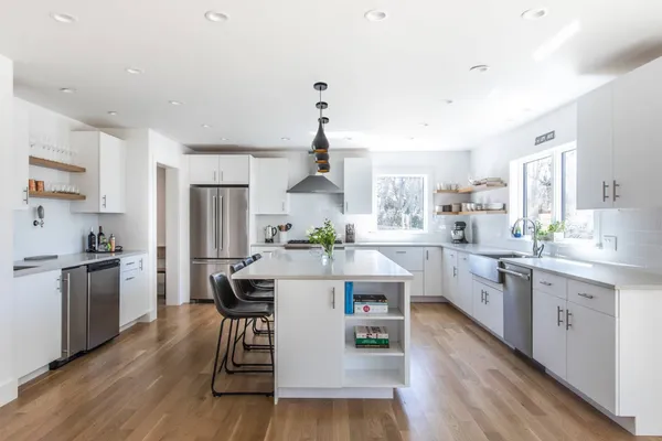 a kitchen with stainless steel appliances a white cabinets and wooden floors