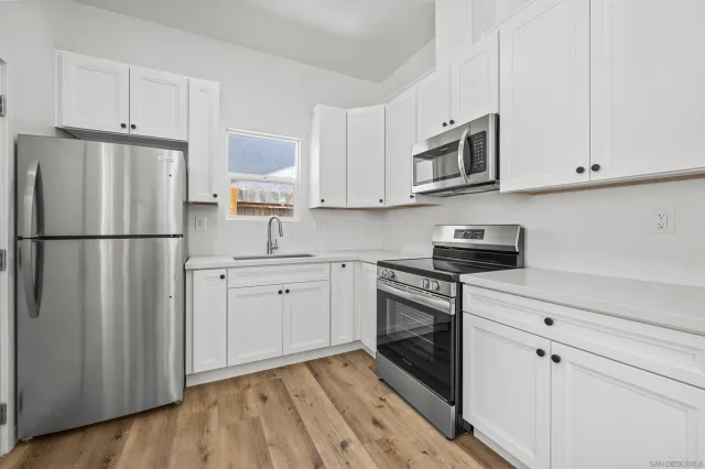 a kitchen with stainless steel appliances white cabinets white stove a sink and a refrigerator