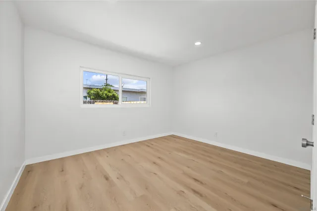 an empty room with wooden floor and window
