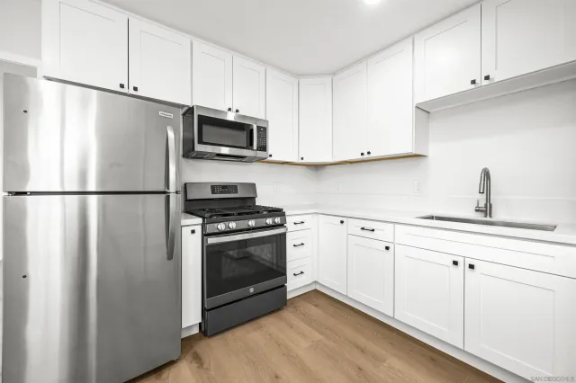 a kitchen with cabinets stainless steel appliances and wooden floor