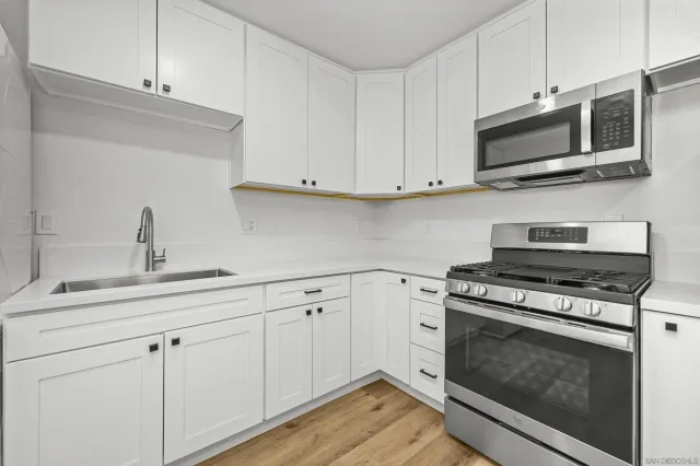 a kitchen with stainless steel appliances granite countertop grey cabinets a stove a sink and dishwasher