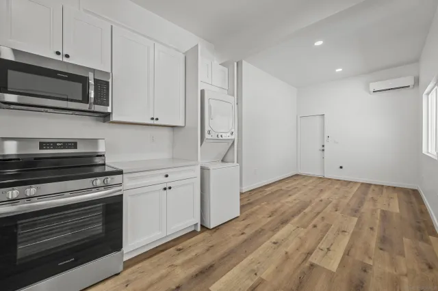 a kitchen with granite countertop white cabinets stainless steel appliances and wooden floor