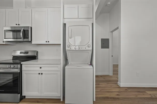 a kitchen with stainless steel appliances white cabinets and a wooden floor