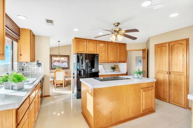 a kitchen with stainless steel appliances kitchen island granite countertop a refrigerator a stove top oven a sink dishwasher and wooden cabinets