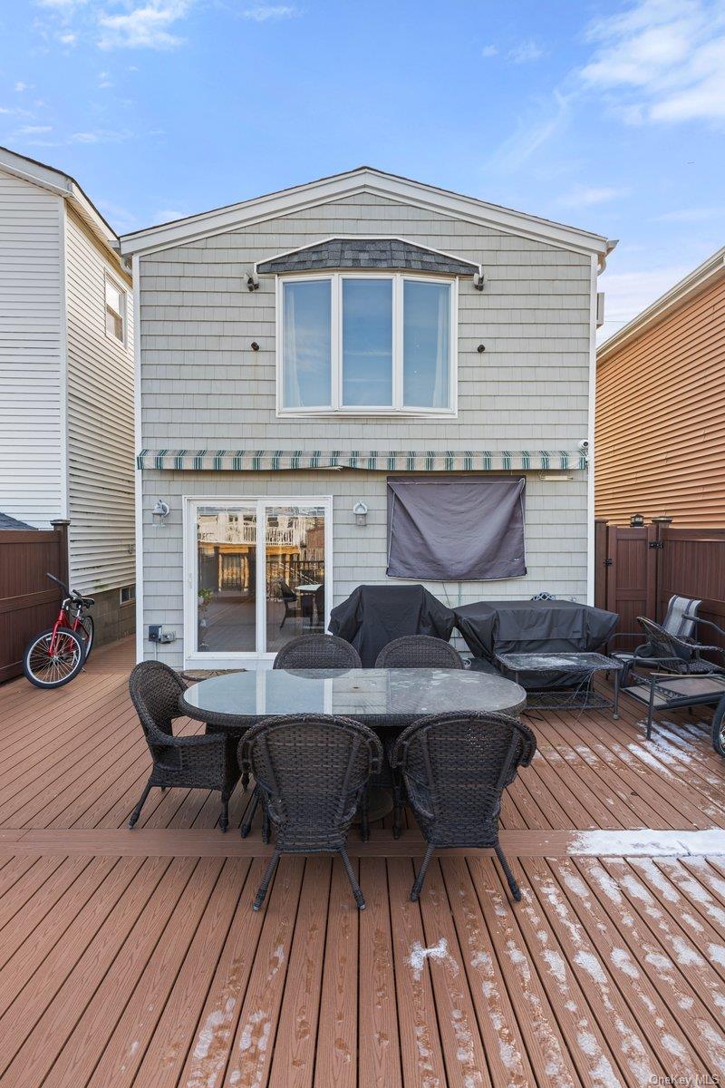 19 West 13th Road Queens, NY 11693 - Photo 15 of 19 a view of a roof deck with table and chairs a barbeque with wooden floor and fence
