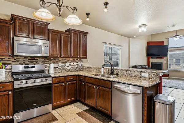 a kitchen with stainless steel appliances granite countertop a sink a stove and a refrigerator