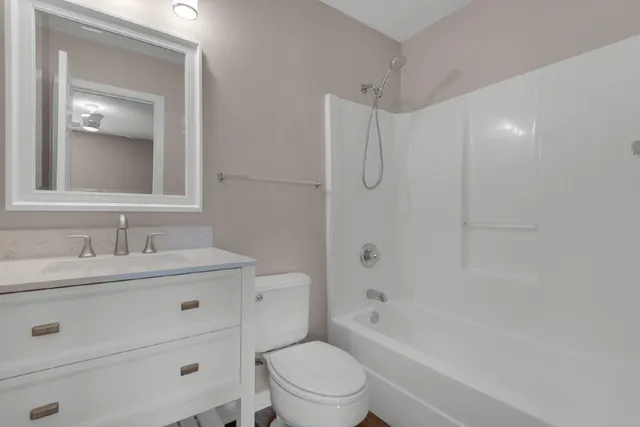 a bathroom with a toilet a sink a mirror a bathtub and vanity